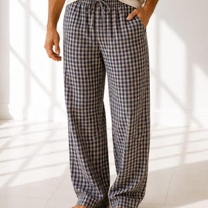 May include: Full-length lounge trousers featuring a navy blue and beige checkered pattern. The trousers have a relaxed fit, a straight leg silhouette, and an elasticated waistband with a matching fabric drawstring tie at the centre front.