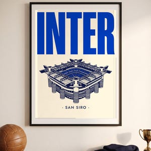 May include: A framed poster featuring a blue and cream graphic illustration of the San Siro stadium. The word INTER is printed in large blue capital letters at the top, and the text SAN SIRO is centered below the stadium illustration.