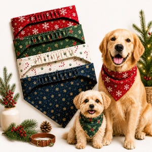 Può includere: Una collezione di quattro bandane triangolari per animali domestici con motivi natalizi in rosso, verde, crema e blu navy. Due cani indossano bandane con stampe di fiocchi di neve e agrifoglio, con un collare in pelle marrone in primo piano.