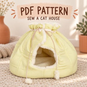 Puede incluir: Una casa para gatos de color amarillo pálido con cierre de cordón, que presenta un forro y ribete de piel sintética blanca. La parte superior de la imagen muestra el texto PDF PATTERN SEW A CAT HOUSE en letras marrones sobre un fondo melocotón.