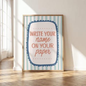 Könnte beinhalten: Ein rechteckiges Wandbild in einem Holzrahmen mit hellblau-weiß gestreiftem Hintergrund. In der Mitte befindet sich eine cremefarbene, gewellte Form mit dem Text "WRITE YOUR name ON YOUR paper" in korallenroter und dunkelblauer Schrift.