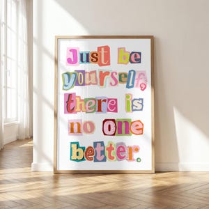 Może przedstawiać: Oprawiony wydruk artystyczny z napisem "Just be yourself, there is no one better." Słowa składają się z pojedynczych liter o różnych krojach, rozmiarach i żywych kolorach, ułożonych w stylu listu z wycinków gazet na białym tle.