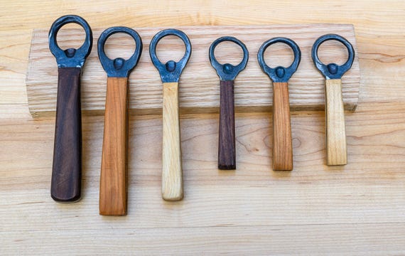 A blacksmith actually hammered this bottle opener into existence — the visible forge marks and wood handle make it the antithesis of every generic bar tool.