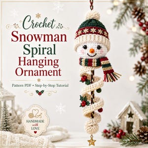 May include: A crochet snowman spiral hanging ornament featuring a white snowman head with a dark green and red patterned beanie, a matching scarf, and a long cream-colored spiral tail decorated with small red berries and green leaves, ending in a gold star.