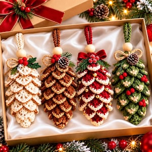 May include: Four crocheted pinecone ornaments in a gift box. The ornaments are cream, brown, red with white trim, and green with red berries. Each features a wooden bead, a small bow, and a hanging loop. The box is lined with white satin.