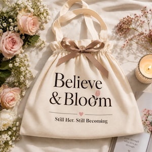 Peut inclure: Un sac fourre-tout en toile cr&egrave;me avec un cordon de serrage et un n&oelig;ud en ruban de satin marron sur le dessus. Le sac porte l'inscription "Believe & Bloom" en marron fonc&eacute;, une petite ic&ocirc;ne de tulipe rose et "Still Her. Still Becoming".