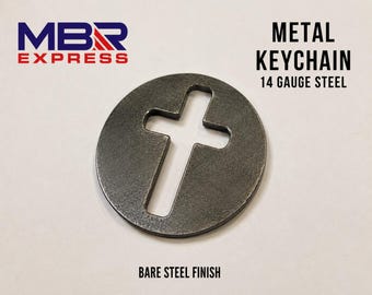 Pode incluir: Um porta-chaves circular de metal feito de aço de calibre 14 com acabamento em aço bruto. O centro do disco apresenta um recorte em forma de cruz. O texto MBR EXPRESS, METAL KEYCHAIN, 14 GAUGE STEEL e BARE STEEL FINISH aparece na imagem.