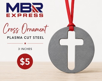 Pode incluir: Um ornamento circular de aço cinzento com uma forma de cruz recortada, suspenso por uma fita vermelha. O texto MBR EXPRESS, Cross Ornament, PLASMA CUT STEEL, 3 INCHES e $5 é visível. O ornamento mede 7,62 cm de diâmetro.