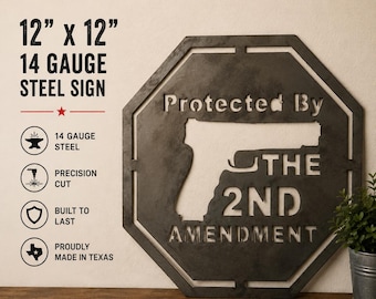 Pode incluir: Uma placa octogonal de aço de calibre 14 medindo 30,48 cm por 30,48 cm com acabamento metálico escuro. A placa apresenta uma silhueta recortada de uma arma de fogo e o texto "Protected By THE 2ND AMENDMENT".