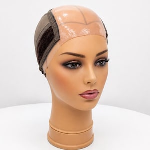 May include: A wig cap featuring a translucent silicone top section designed to mimic a scalp, combined with a brown fabric base. The cap includes a dark brown velvet strip along the sides and back, constructed with fine mesh material for a secure fit.