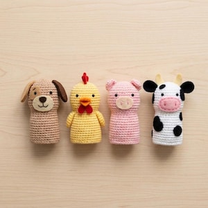 Puede incluir: Un conjunto de cuatro marionetas de dedo de ganchillo que incluye un perro color canela con orejas marrones, un pollo amarillo con cresta roja y pico naranja, un cerdo rosa con hocico plano y una vaca blanca con manchas negras y cuernos amarillos.