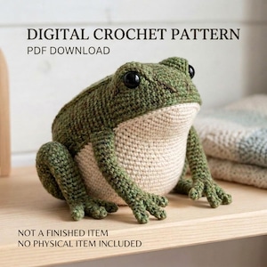 May include: A digital crochet pattern PDF download for a stuffed frog. The frog is made of dark green yarn on the back and light cream yarn on the belly, featuring large black plastic eyes. Text reads: DIGITAL CROCHET PATTERN PDF DOWNLOAD. NOT A FINISHED ITEM.