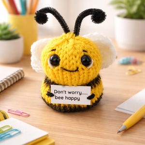 May include: A handmade yellow and black crocheted bee with large black eyes and white wings. The bee holds a sign that reads "Don't worry..... bee happy". The bee has black pipe cleaner antennae. A cheerful, whimsical decorative item.
