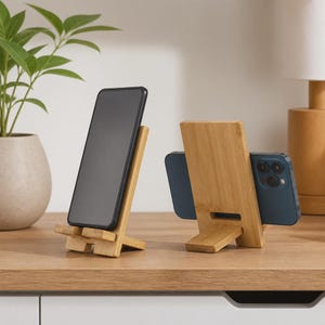 Op de afbeelding: Twee lichtbruine bamboe telefoonstandaards, waarvan er één een smartphone in verticale positie houdt en de andere een smartphone in horizontale positie. De standaards hebben een eenvoudig tweedelig ontwerp met een gladde houtnerf.