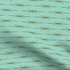 May include: A repeating pattern of gold starbursts on a light blue background. The starbursts are made up of thin lines that radiate outwards from a central point.