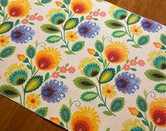 May include: A white table runner with a colorful floral pattern. The flowers are red, yellow, orange, blue, green, and purple. The runner has a white background with a subtle floral pattern.