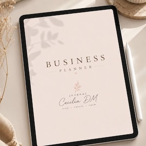 Puede incluir: Una tableta digital que muestra un planificador de negocios con fondo beige claro. El texto dice BUSINESS PLANNER, JOURNAL Cecilia DM y PLAN CREATE GROW. Un lápiz óptico blanco descansa junto a la pantalla, que incluye un gráfico floral.