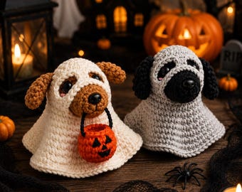 May include: Two crocheted dog figures dressed as ghosts. The left figure is a brown dog in a cream-colored ghost costume holding a small orange jack-o'-lantern bucket. The right figure is a gray and black dog in a gray ghost costume.