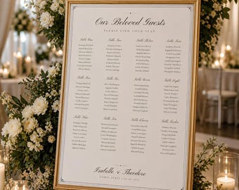 May include: A rectangular wedding seating chart in a gold frame, featuring the text Our Beloved Guests and Please Find Your Seat, followed by twelve tables of names and the names Isabelle & Theodore with the location Como, Italy and date 09.09.2027.