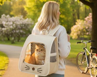 Puede incluir: Una mochila transportadora para mascotas de color crema con una ventana frontal transparente, un panel lateral de malla y un diseño de cara de gato estilizada con bigotes y nariz. La mochila cuenta con correas ajustables para los hombros.