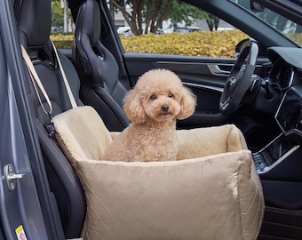 Puede incluir: Un asiento de coche para mascotas acolchado de color beige con forro interior de vellón color crema, con correas ajustables para una fijación segura, ocupado por un perro pequeño de color marrón claro y pelo rizado sentado en el centro.