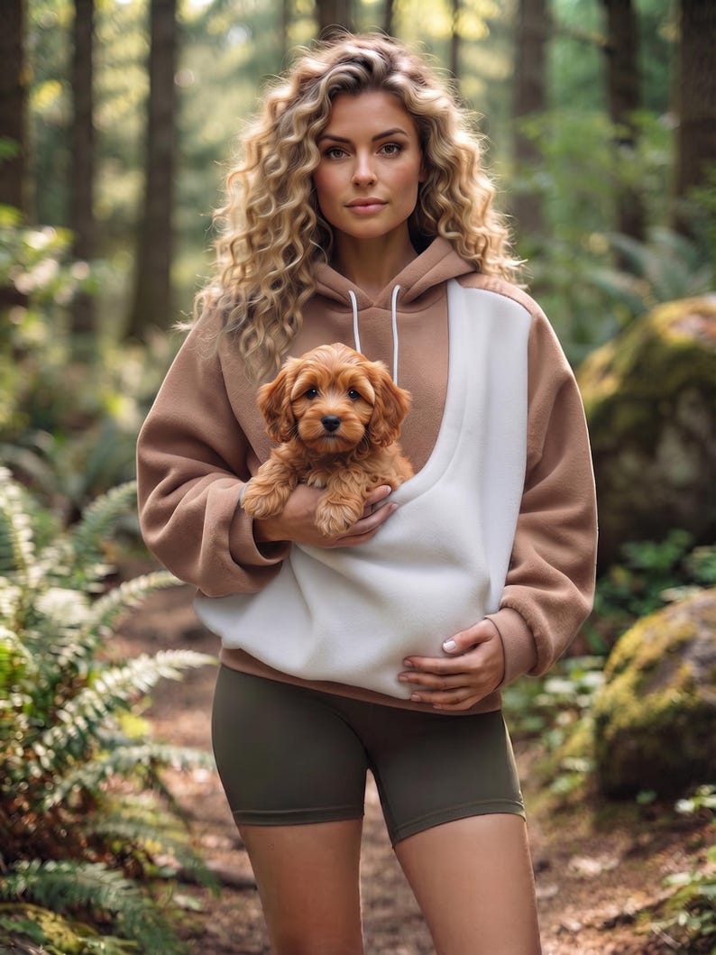 May include: A tan and white color-blocked hooded sweatshirt with a large front pouch pocket, worn with olive green athletic shorts. The sweatshirt features a drawstring hood and long sleeves, providing a casual look for outdoor activities.