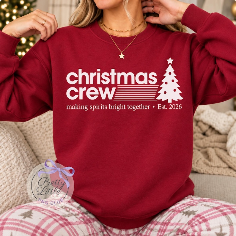 May include: A dark red long-sleeve sweatshirt featuring white text that reads "christmas crew" with a graphic of a stylized Christmas tree, followed by the text "making spirits bright together &bull; Est. 2026" printed on the front.