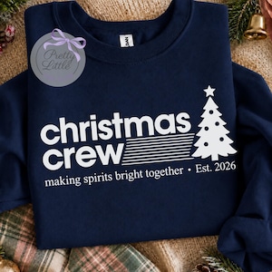May include: A navy blue crewneck sweatshirt featuring white screen-printed text that reads "christmas crew" with a stylized Christmas tree graphic. Below the text, it says "making spirits bright together &bull; Est. 2026" in white lettering.