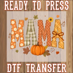 May include: A Ready to Press DTF transfer featuring the word MAMA in large block letters with various autumn patterns including white daisies, green plaid, orange polka dots, and yellow plaid, accented by a pumpkin, leaves, and a bow.