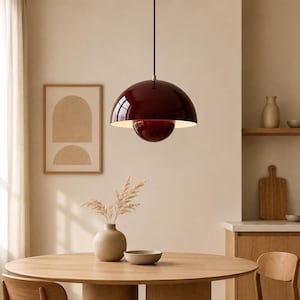 May include: A glossy dark burgundy pendant light with a dome-shaped shade and a smaller matching semi-spherical element underneath, suspended by a thin cord from the ceiling, featuring a smooth finish and a white interior light reflector.