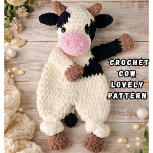 Könnte beinhalten: Ein gehäkeltes Kuscheltier in Kuhform mit weißem Körper, schwarzen Flecken, rosa Schnauze und braunen Hufen. Das Spielzeug hat schwarze Knopfaugen und kleine braune Hörner. Der Text CROCHET COW LOVELY PATTERN steht rechts im Bild.