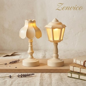 May include: Two cream-colored battery-operated lamps with warm internal lighting. One lamp features a scalloped petal-shaped shade, while the other is a hexagonal lantern style. The word Zenvico is printed in the upper right corner of the image.