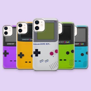 Puede incluir: Cinco fundas para smartphone con diseños de consolas portátiles retro en morado, amarillo, gris, verde lima y cian. Cada funda muestra el logotipo de Nintendo Game Boy o Game Boy Color, una pantalla, una cruceta y botones de control.