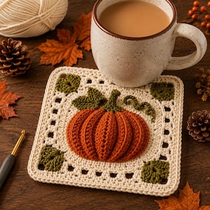 Peut inclure: Un dessous de verre carré au crochet présentant une citrouille orange en relief au centre, accompagnée de feuilles et d'une vrille vertes. L'ouvrage est réalisé en fil crème avec une bordure ajourée, mettant en valeur le travail du crochet.