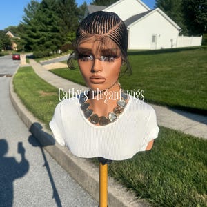 Könnte beinhalten: Ein Schaufensterpuppenkopf mit einer schwarzen Perücke mit komplexen Cornrow-Zöpfen und Lace-Front, gestylt mit feinen Babyhaaren. Die Puppe trägt ein weißes, geripptes Kurzarm-Oberteil und eine klobige silberfarbene Halskette. Text: Cathy's Elegant Wigs.