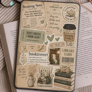 May include: A tablet case covered in book-themed stickers, including a newspaper clipping, a library card, a coffee cup labeled Reading Fuel, and a stack of books. The stickers feature text like Anti-Social Book Club, booktrovert, and various floral illustrations in muted beige and green tones.