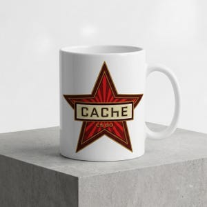 May include: A white ceramic mug featuring a large red star graphic with dark red sunburst rays. Centered across the star is a rectangular cream-colored banner with the black text CACHE and the smaller text CS GO printed underneath.