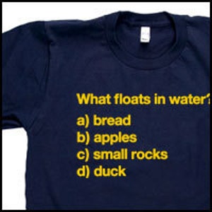 May include: A navy blue t-shirt with yellow text that reads "What floats in water?" and lists four options: a) bread, b) apples, c) small rocks, d) duck.