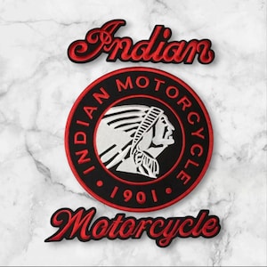 May include: An embroidered patch featuring the Indian Motorcycle logo. The design includes the word Indian in red script above a circular black emblem with a white profile of a person wearing a headdress, surrounded by the text Indian Motorcycle 1901.
