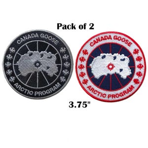May include: A pack of 2 circular embroidered patches measuring 3.75 inches. One patch is black and grey with white snowflake icons, and the other is white, blue, and red with red maple leaf icons. Both feature the text CANADA GOOSE ARCTIC PROGRAM.