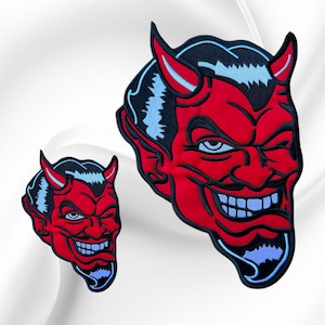 May include: Two embroidered patches featuring a red devil face with black hair, pointed horns, and a goatee. The design includes light blue highlights on the horns, hair, and teeth, with a wide, grinning expression and a tongue sticking out.
