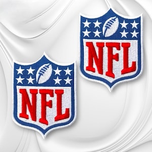 May include: Two embroidered shield-shaped patches featuring the NFL logo. Each patch has a blue background with white stars, a white football graphic, and the red letters NFL in a bold font, all outlined with a white border on a white fabric.