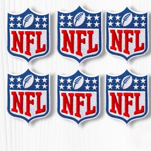 May include: Six embroidered shield-shaped patches featuring the NFL logo. Each patch displays a blue upper section with white stars and a white football, and a white lower section with the red letters NFL in a bold, block font with a blue border.