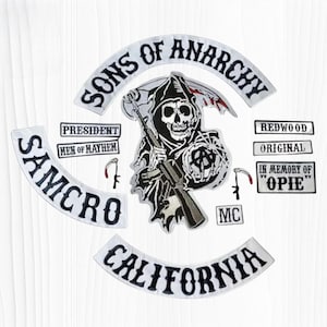 May include: A set of embroidered patches featuring a central grim reaper holding a rifle and scythe, surrounded by text including SONS OF ANARCHY, SAMCRO, CALIFORNIA, PRESIDENT, MEN OF MAYHEM, REDWOOD, ORIGINAL, and IN MEMORY OF OPIE with MC.