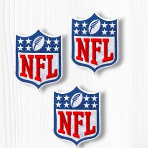 May include: Three shield-shaped embroidered patches featuring the NFL logo. Each patch has a blue top section with white stars and a white football, and a white bottom section with the red letters NFL. The edges are finished with white stitching.