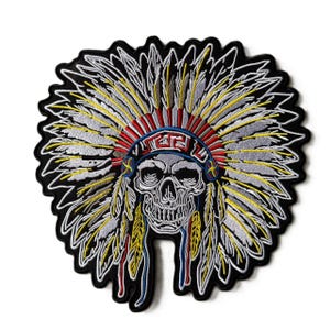 May include: An embroidered patch featuring a human skull wearing a large feathered headdress. The skull is white with black shading, and the headdress consists of white, yellow, and red feathers with a blue and red patterned headband border.
