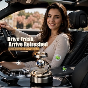 Può includere: Un deodorante per auto circolare color oro con una sfera centrale fluttuante, che presenta il testo 'Drive Fresh, Arrive Refreshed' e 'Pure Fragrance, Every Journey' sovrapposto all'immagine, in un interno di veicolo scuro.