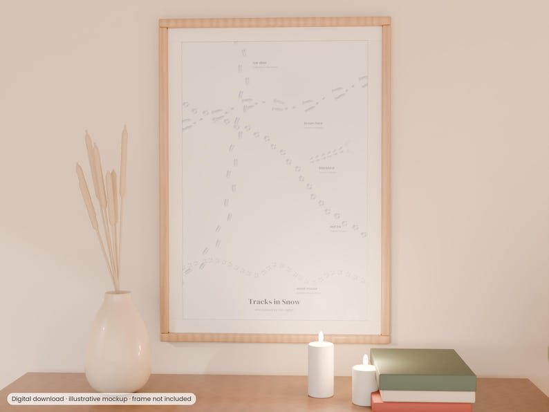 May include: A framed wall art print titled Tracks in Snow featuring a white background with various gray animal footprint patterns and labels. The print is displayed in a light wood frame alongside a white vase with dried stems and candles.