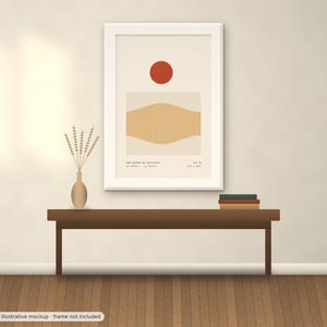 May include: A framed wall art print featuring a solid red circle above a rectangular block of vertical tan lines with a curved wave pattern. The text "LES VUES DE NATURE" is printed at the bottom along with smaller coordinates and date details.