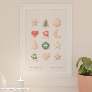 Könnte beinhalten: Ein weiß gerahmter Wandkunstdruck mit einem Raster aus zwölf illustrierten Weihnachtsplätzchen, darunter Sterne, Tannenbäume, Herzen, ein Fäustling und eine Mondsichel. Der Text THE COOKIE TRAY und baked for december steht am unteren Rand.